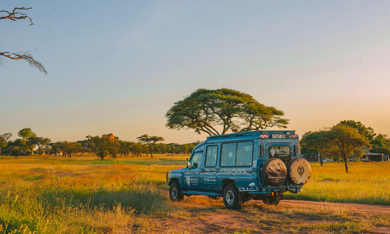A safari vehicle parked in the vast African savannah during sunset, ideal for adventure and travel themes.